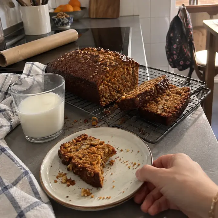 Bizcocho de zanahoria y nueces en la rejilla, con dos trozos cortados y uno a medio comer en un plato